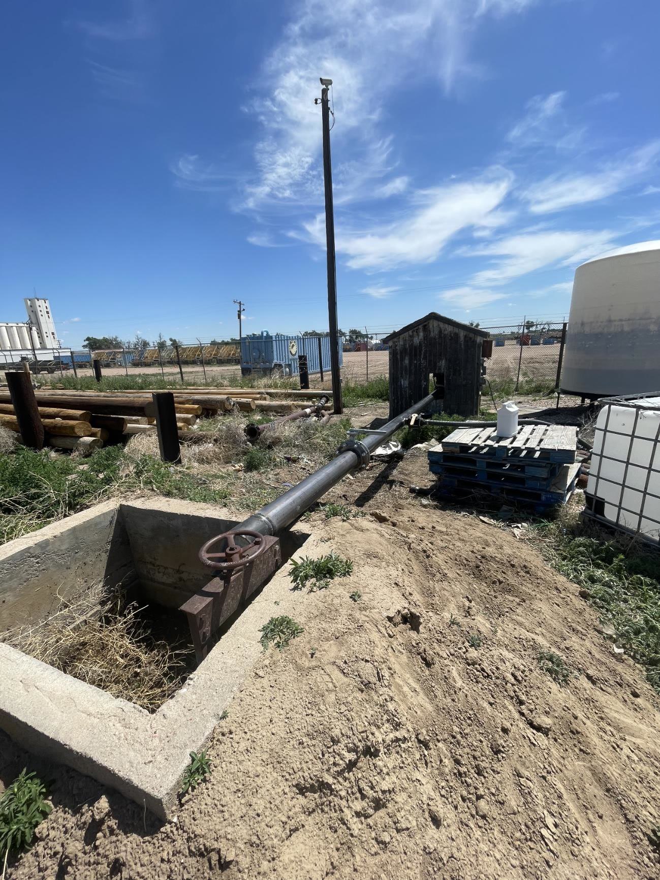 Steel pipe and valve spanning a concrete irrigation pit