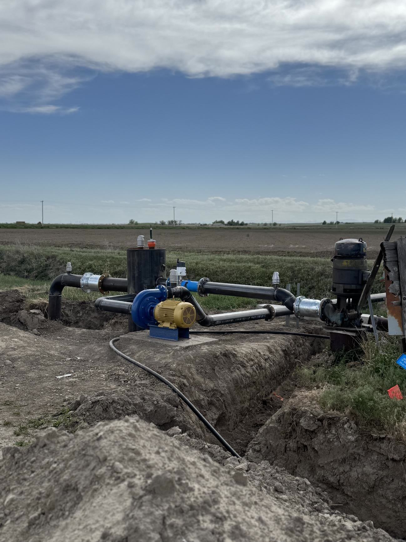 Pump and welded steel pipeline in a trench at the edge of a field